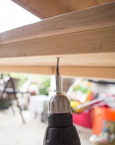 a black and silver light hanging from a wooden beam