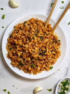 a white plate topped with noodles and chopsticks