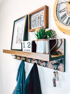 a wooden shelf with some plants and pictures on it next to a wall mounted clock