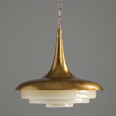 a gold colored pendant light hanging from a chain