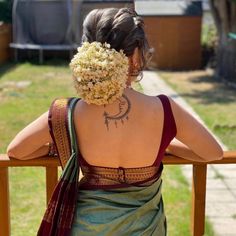 the back of a woman's head with flowers in her hair, sitting on a bench