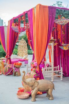 an elephant statue in front of a decorated stage with orange and pink draping