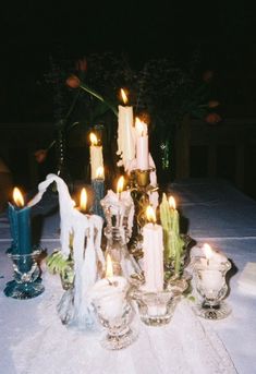 a table topped with lots of candles on top of a white cloth covered tablecloth