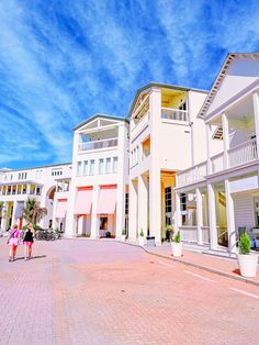 two people are walking in front of some white buildings