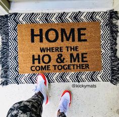 someone standing in front of a door mat that says home where the ho & me come together