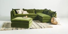 a living room with a large green couch and footstool in front of a rug