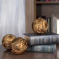 three golden decorative objects sitting on top of books next to a framed photo and an old book