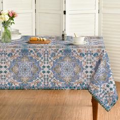 a blue table cloth with an ornate design on it and flowers in vases next to it