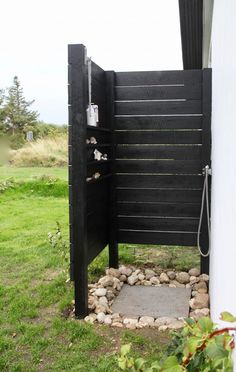 an outdoor shower in the middle of a grassy area with rocks and grass around it