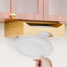 a person holding a white plate in front of a wooden cabinet with the number 10 inch on it