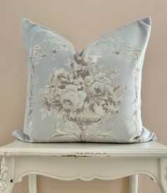 a blue pillow sitting on top of a white table next to a wooden shelf and chair