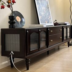 an entertainment center with a record player and flowers on it's sideboard in a living room