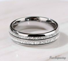 two wedding bands with white gold inlays on a marble surface, the band has been