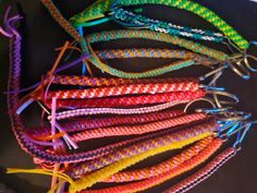 there are many different colors of braided bracelets on the black table and one is multicolored