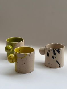 three ceramic cups with different designs on them