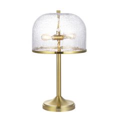 a glass and brass table lamp with a clear shade on the base, against a white background