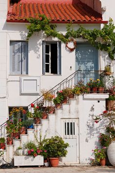 a white building with flowers and plants growing on it's balconies in front of the door