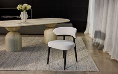 a dining room table with two chairs and a vase on the rug next to it