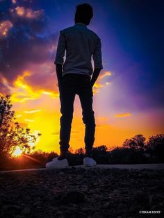 a man standing on top of a hill at sunset