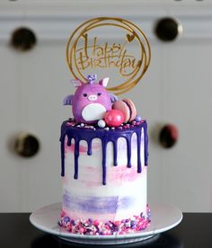 a birthday cake with an animal on top and purple icing dripping down the side