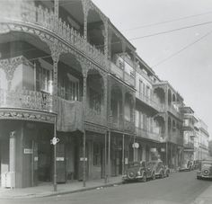 an old black and white photo of cars parked on the street in front of buildings