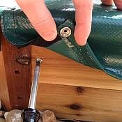 a hand reaching for a green purse on top of a wooden box with rocks underneath it