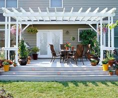 a white pergolan sitting on top of a patio next to potted plants