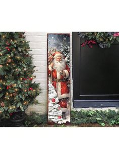 a christmas door hanger with a santa clause on it and trees in the background