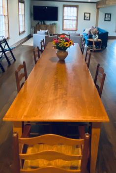 a large wooden table with chairs around it and a vase on the table in front of it