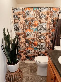 a bathroom with a cactus shower curtain next to a toilet