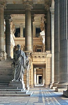 a statue in the middle of a building with many pillars and steps leading up to it