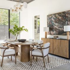 the dining room table is surrounded by white chairs and an area rug that has a checkered pattern on it