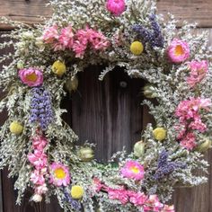 a wreath made out of flowers on top of a wooden door with purple and pink flowers