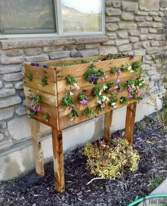 a wooden planter filled with flowers next to a brick wall and window sill