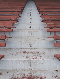 some red wooden benches with numbers painted on the side and one in the middle is empty