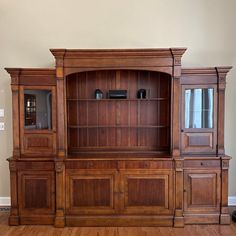 a large wooden entertainment center with glass doors on the front and side panels, in a living room