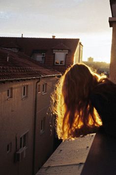 a woman standing on top of a roof next to a tall building