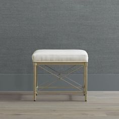 a white bench sitting on top of a hard wood floor next to a gray wall