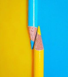 two pencils sticking out of the side of a blue and yellow wall next to each other