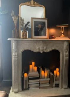 a fire place with candles in front of it and a mirror on the top shelf