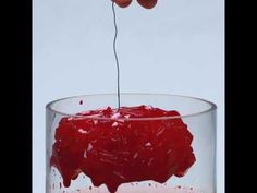 someone is dipping something into a glass with red liquid