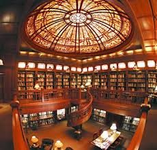 the interior of a library with many bookshelves and tables in it, as well as a circular stained glass ceiling