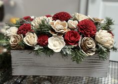 a wooden box filled with lots of red and white flowers on top of a table