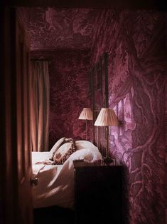 a bed with two lamps on either side of it and a purple wall behind it