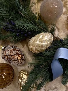 christmas decorations are arranged on a table with blue ribbon and gold baubles in the background