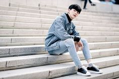 a young man sitting on steps with his legs crossed