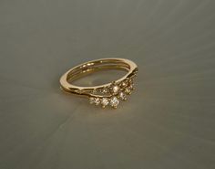 a gold ring with three small diamonds on the top and bottom, sitting on a gray surface