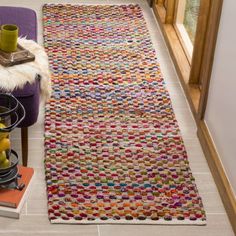 a multicolored rug is on the floor next to a purple chair and vase