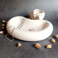 a white bowl with a chain around it and some nuts on the ground next to it