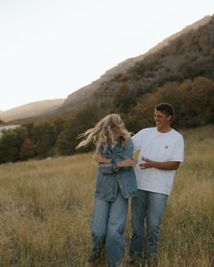 a man and woman standing in tall grass